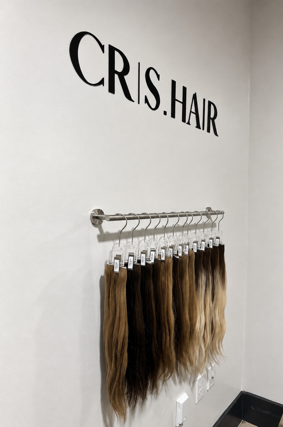 CRIS.HAIR wall logo above the studio's curated hair extension display
